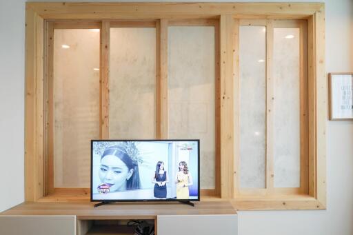 Modern living room with a large TV and wooden storage compartments