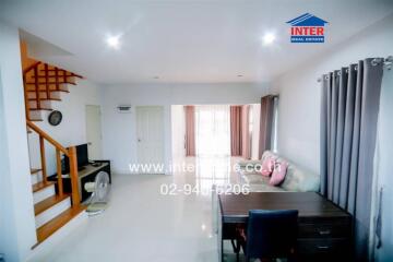 Spacious living room with natural light, featuring a staircase and modern furnishing