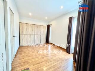 Spacious bedroom with wooden flooring and elegant curtains