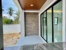 Stylish covered patio with modern finishes featuring marble flooring and a brick accent wall