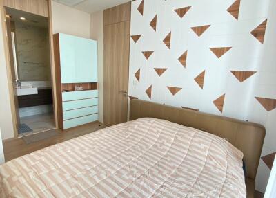 Modern bedroom with stylish geometric wallpaper and direct bathroom access