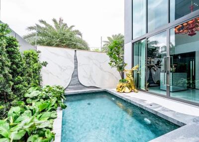 Modern outdoor pool adjacent to a stylish home with large glass windows and marble walls