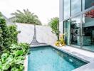 Modern outdoor pool adjacent to a stylish home with large glass windows and marble walls