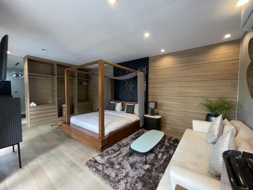 Spacious bedroom with modern design featuring a large bed, stylish sofa, and wooden accents