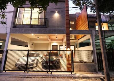 Modern two-story residential building with illuminated facade and secured parking area