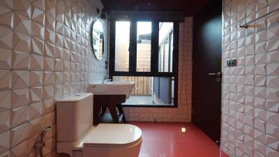 Modern bathroom with geometric tiles, large window, and red flooring