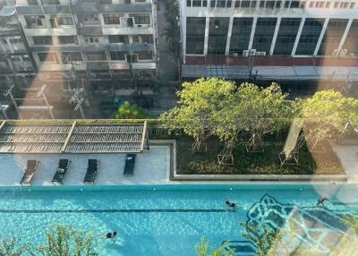 Aerial view of a residential building complex with an outdoor swimming pool surrounded by lush greenery