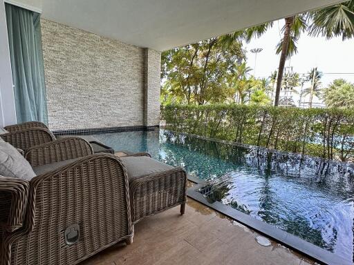 Spacious patio with wicker furniture overlooking an infinity pool and tropical palm trees