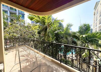 Spacious balcony with lush greenery view and outdoor furniture