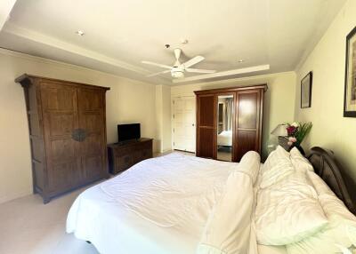 Spacious bedroom with large bed, wooden furniture, and ceiling fan