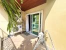 Bright and compact balcony area with sliding glass door and tropical plant