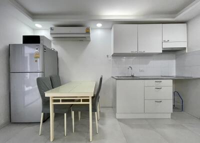 Modern kitchen with dining area featuring a refrigerator, table, and cabinets