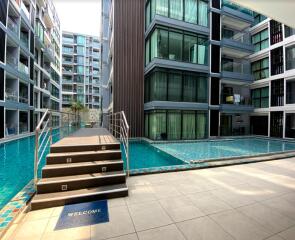 Modern residential complex with outdoor swimming pool and welcome sign