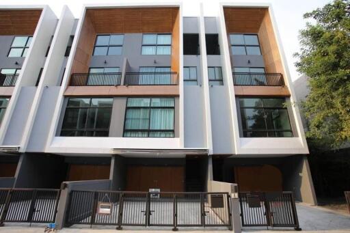 Modern multi-story residential building with wooden and gray panel facade