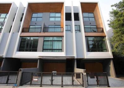 Modern multi-story residential building with wooden and gray panel facade