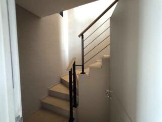 Modern staircase with a wooden railing and bright lighting