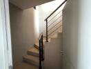 Modern staircase with a wooden railing and bright lighting