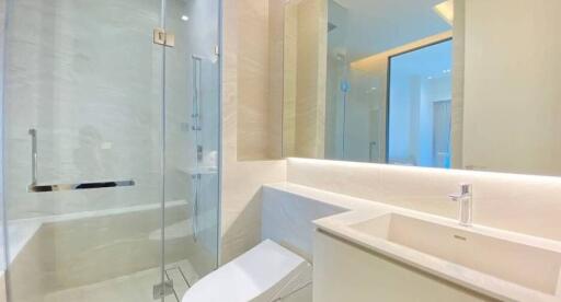 Modern bathroom with sleek design featuring a walk-in shower, glass enclosure, and white vanity