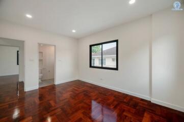 Spacious and well-lit bedroom with glossy hardwood flooring