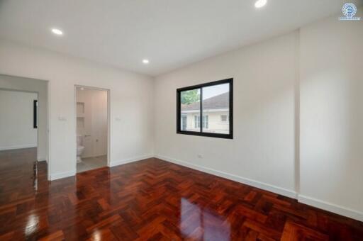 Spacious and well-lit bedroom with glossy hardwood flooring