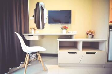 Modern and compact living space with integrated work desk, wall-mounted TV, and storage units