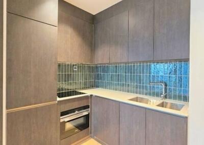 Modern compact kitchen with wooden cabinetry and blue tiled backsplash