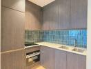 Modern compact kitchen with wooden cabinetry and blue tiled backsplash