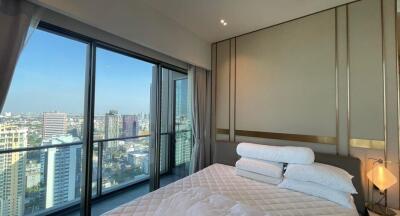 Modern high-rise apartment bedroom with large windows offering a city view