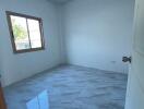 Spacious empty bedroom with large window and tiled floor