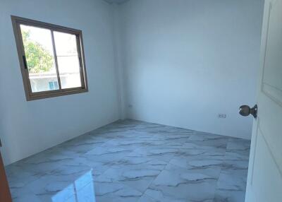 Spacious empty bedroom with large window and tiled floor