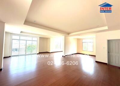 Spacious and brightly lit living room with hardwood flooring and multiple windows