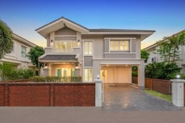 Modern two-story house with balcony and driveway during twilight