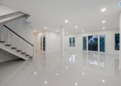 Spacious and modern living area with gleaming floor tiles, natural light, and staircase