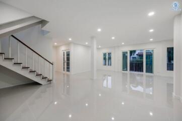 Spacious and modern living area with gleaming floor tiles, natural light, and staircase