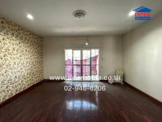 Spacious bedroom with wooden flooring and large window