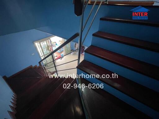 Wooden staircase in a home with blue walls and a view of the upper landing