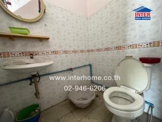 Compact bathroom with basic amenities, tile flooring, and decorative border