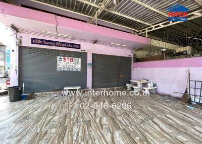 Spacious commercial space with shutters down and contact information visible