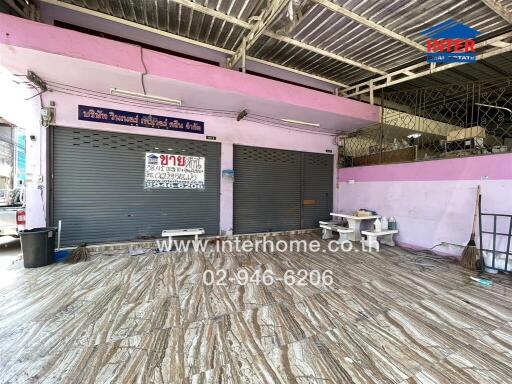 Spacious commercial space with shutters down and contact information visible