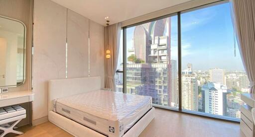 Modern bedroom with large window offering city views in a high-rise apartment
