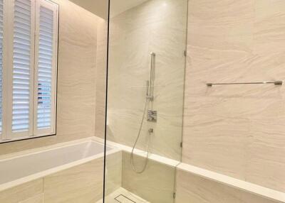 Modern bathroom with bathtub and shower combination, light marble walls and plantation shutters