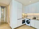 Modern white kitchen with built-in appliances and washing machine