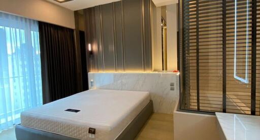 Modern bedroom with stylish design featuring a large bed, elegant lighting, and window blinds