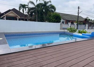 Modern residential outdoor swimming pool with wooden decking and surrounding neighborhood