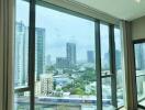 Bright bedroom with large floor-to-ceiling windows offering a city view