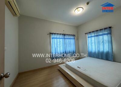 Bedroom with bed, wooden floor, and blue curtains