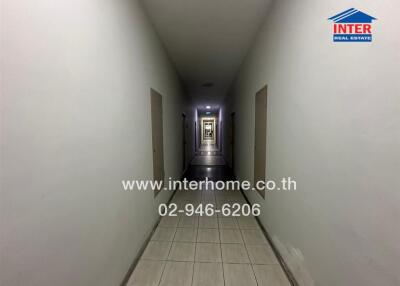 Long narrow hallway in a building with tiled floors and multiple doors