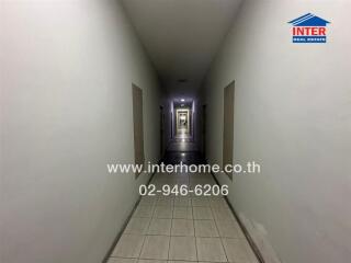 Long narrow hallway in a building with tiled floors and multiple doors
