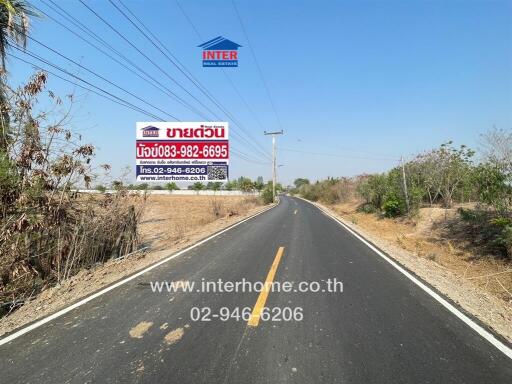 Asphalt road with real estate advertising billboard in a rural setting