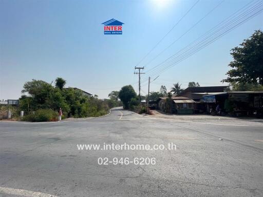 Road intersection near residential area with clear skies and real estate signage